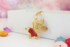 Detailansicht eines Adleranhängers mit goldenen Flügeln und roten Strasssteinen
