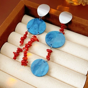 Detail of silver drop earrings with blue acrylic discs and red natural stone beads