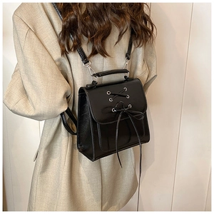 Detail of black glossy leather backpack with silver eyelets and cross-lace design
