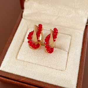 Close-up of vintage gold twisted hoop earrings with faceted deep red glass beads