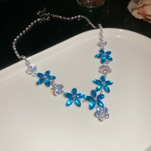 Detailed close-up of blue floral crystal necklace with teardrop petals on white plate