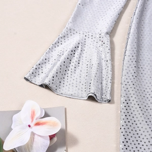 Détail de robe à paillettes argentées avec manches cloches et texture brillante