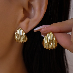 Gros plan de boucles d'oreilles dorées en forme d'éventail avec texture plissée rétro