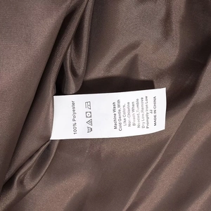 Detailansicht des Pflegeetiketts auf brauner Steppjacke mit Materialinfos aus Polyester