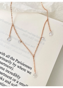 Detailed view of rose gold teardrop zircon tassel necklace on vintage book pages
