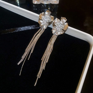 Close-up of silver long tassel earrings with flower pearl studs on black velvet