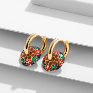 Detailaufnahme goldener Creolen mit farbenfrohen Emaille-Blumenanhängern auf Weiß