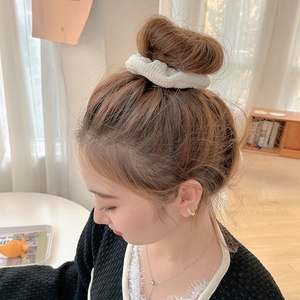 Elegant woman wearing a white plush scrunchie with minimalist gold jewelry