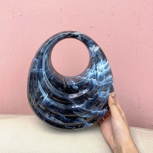Detail of blue marble acrylic evening bag with unique wave texture and cutout handle