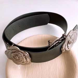 Détail de la ceinture en cuir noir avec des ornements de roses en métal argenté