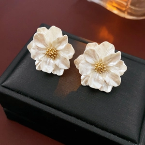 Detailed close-up of floral resin earrings with pearlescent finish on a black jewelry box