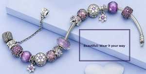Detail of purple Murano glass beads and floral charms on a silver snake chain bracelet