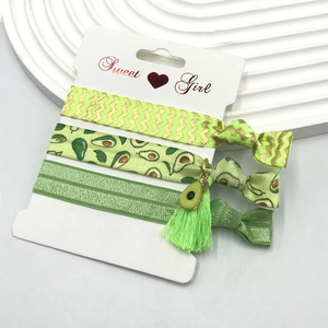 Three-piece set of avocado green hair ties with prints and charms on a Sweet Girl card
