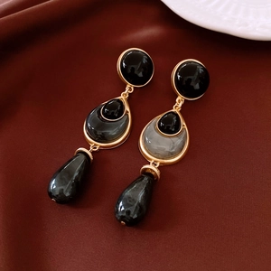 Detailed view of vintage gold-tone earrings with black resin beads on silk background