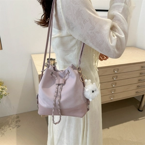 Pink PU leather bucket bag with metal chain and plush charm on female model
