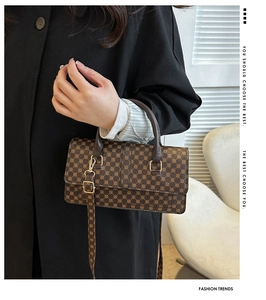 Detail of classic brown monogram handbag with gold buckle and adjustable shoulder strap