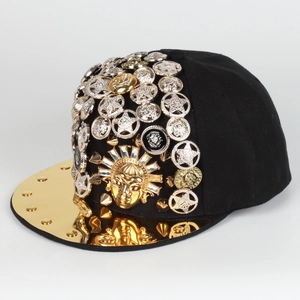 Close-up of golden sun face emblem and mixed metal studs on black snapback cap