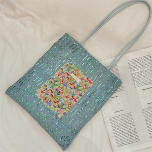 Close-up of light blue canvas tote bag with floral patch and sequin embellishments