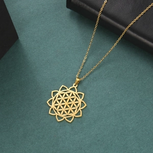 Macro view of gold stainless steel hollow flower of life pendant on green background