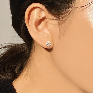 Close-up of elegant four-prong zircon stud earring worn by a model in warm lighting