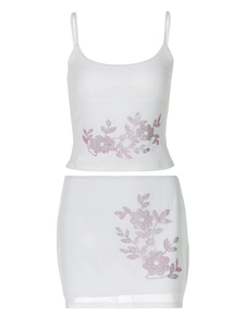 Detail of white two-piece skirt set featuring pink floral rhinestone patterns on white fabric