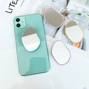 Irregular cartoon mirror phone grip stand in gold, silver, and purple on a green phone