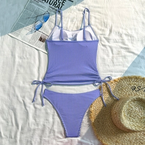 Close-up of blue and white striped bikini with side drawstrings on a sunny beach background