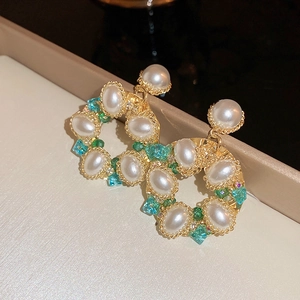 Close-up of vintage flower earrings with pearls and green crystals on gold frame