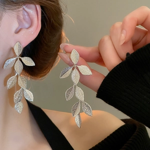 Detailed close-up of elegant silver leaf tassel earrings on model with metallic finish