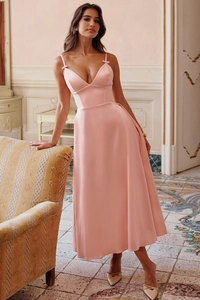 Detail of pink satin V-neck dress showing delicate bow straps and glossy fabric texture