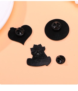 Detail view of black enamel pin backings with heart shapes and butterfly clutch pins