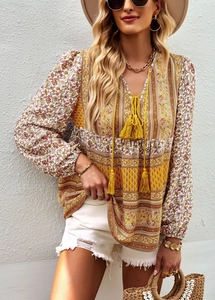 Bohemian V-neck printed blouse styled with white shorts and a straw handbag in full view