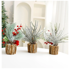 Three mini snow-flocked Christmas trees with red berries and pine cones in wood-stump pots