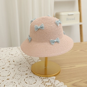 Detail showing pink straw sun hat with light blue mesh bows on a golden display stand