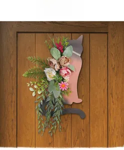 Detailed view of cat-shaped wooden wall plaque with pink artificial flowers on a wooden door