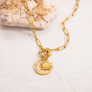 Macro view of gold celestial sun and moon pendant with crystals on paperclip chain