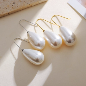 Elegant water drop pearl earrings with gold and silver hooks on a natural textured background
