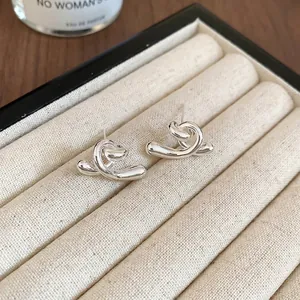 Boucles d'oreilles clous torsadées en métal argenté poli dans un organiseur de bijoux beige