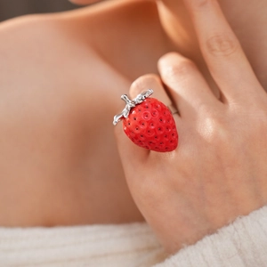 Macro di un anello a fragola in resina rossa con foglie argentate sul dito