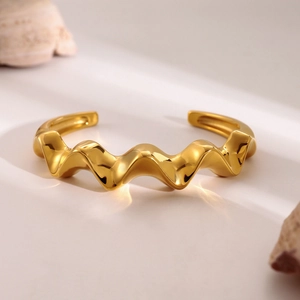 Macro shot of 18k gold wave bangle showing fluid ripples on a minimalist stone