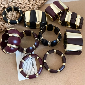 Detail view of retro acrylic bracelets in wine red and black with gold metal accents