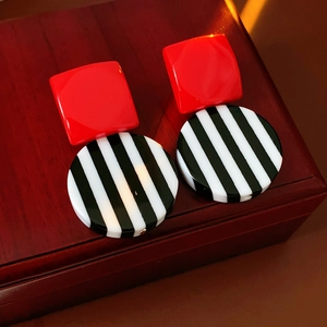 Detail of geometric resin earrings with red square and black and white striped round elements