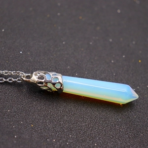 Macro shot of opal hexagonal pendant with silver hollow pattern on dark textured background