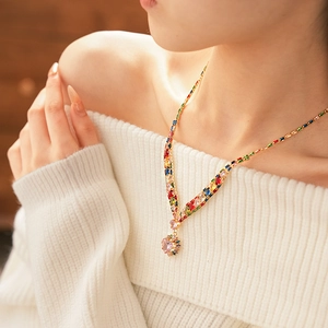 Detail of pink heart crystal pendant on gold necklace with multicolor zircon accents