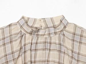 Detailed view of plaid crop top featuring a high collar and double button back closure