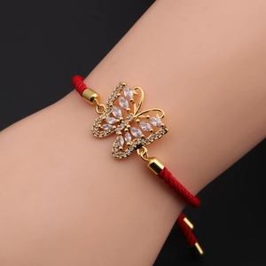 Close-up of a gold butterfly charm with zircon stones on a red woven adjustable bracelet