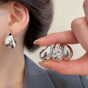 Detailed close-up of textured and polished silver-tone waterdrop geometric stud earrings