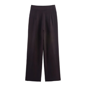 Detail of high-waist black wide-leg trousers with elegant front pleats and draped fabric