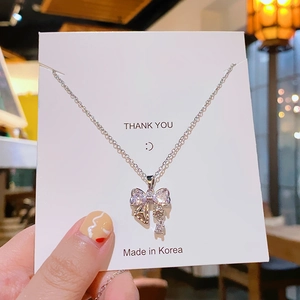 Élégant collier pendentif nœud en argent avec zircons sur un fond lumineux et doux