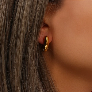 Close-up of a minimalist 18K gold plated stainless steel C-shaped hoop earring on a model